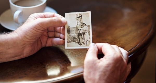 Hands holding an old family photograph at a table